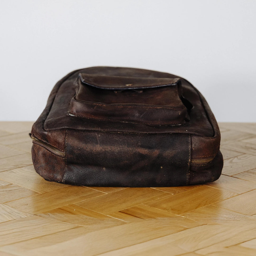 Brown leather bag on a wooden floor with a white background