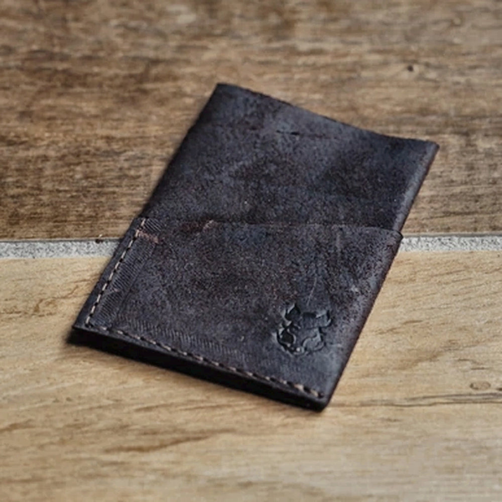 Dark brown leather card wallet on a wooden surface